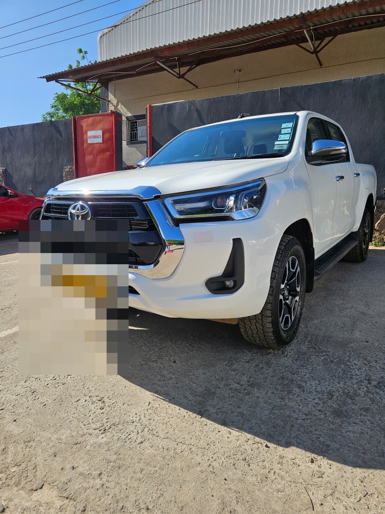 A white Toyota Hilux at the Motor Madness workshop entrance